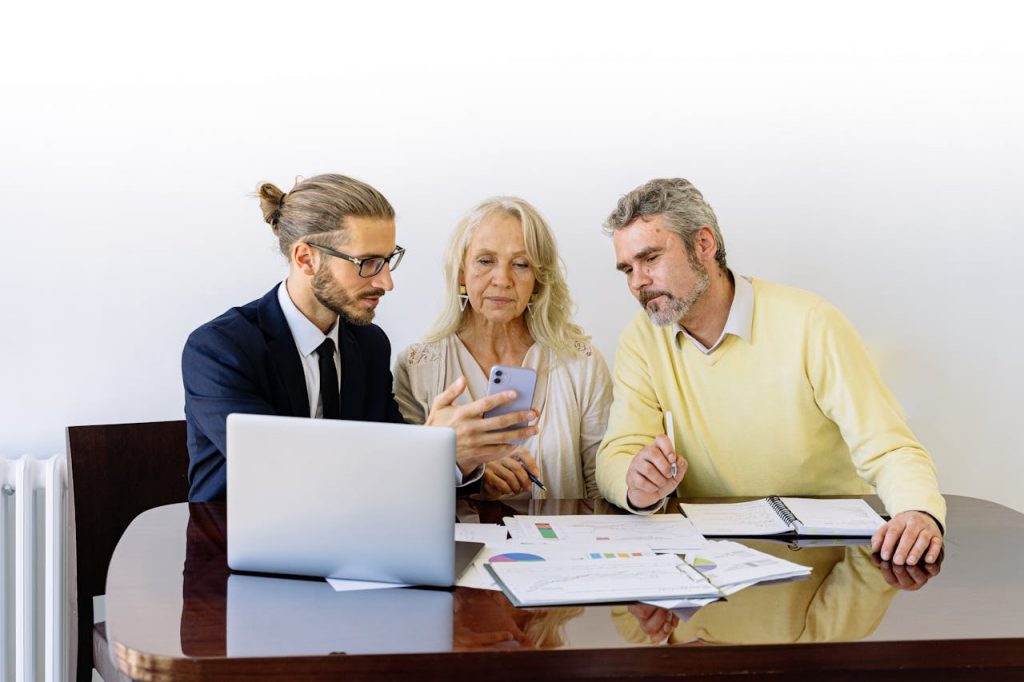 pexels-photo-5816286 Three individuals collaborating on financial documents during a business meeting.